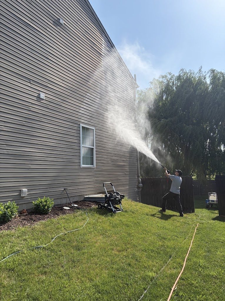 Nico's crew soft washing the siding of a two-story home